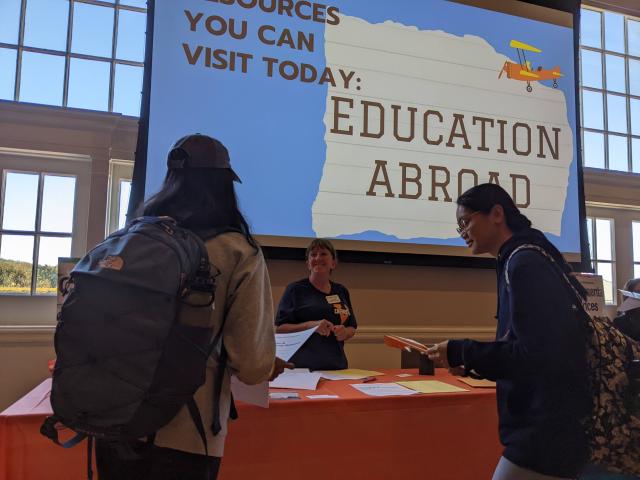 students talking with smiling program staff at a table at the 2022 event